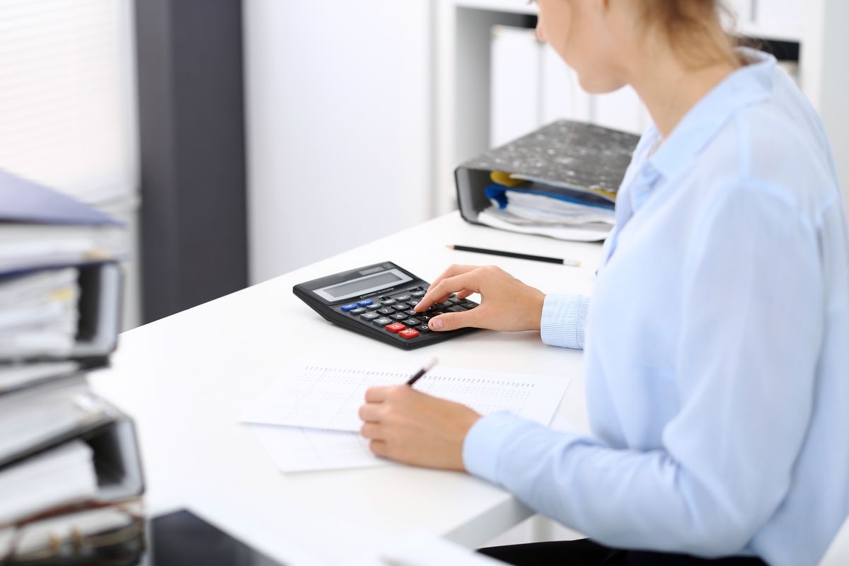 Unknown female bookkeeper or financial inspector calculating or checking balance, making report, close-up. Internal Revenue Service at work with financial document. Tax and audit concept