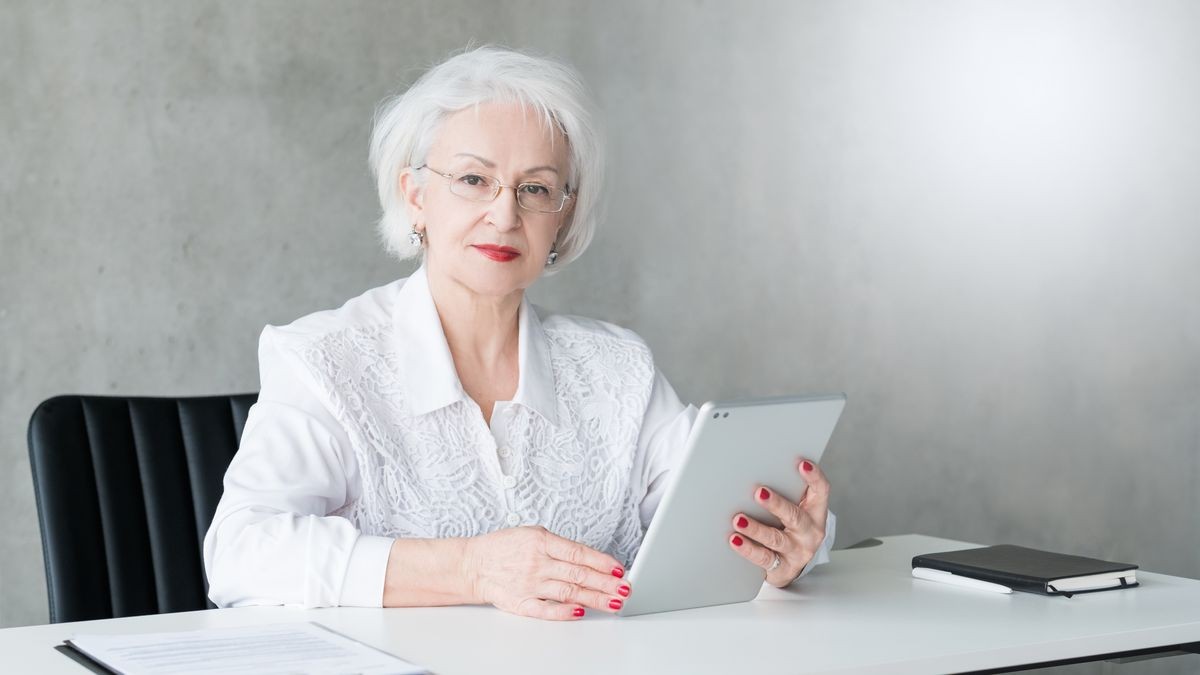 Successful business woman. Head of department. Portrait of confident senior lady sitting at desk, holding tablet.